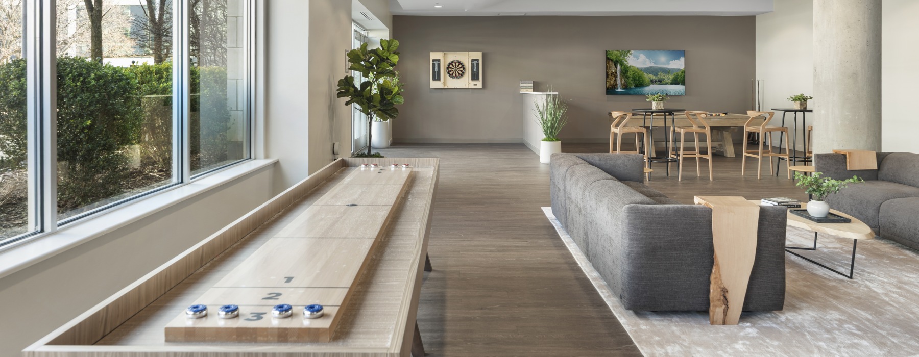 Resident club room at 75 Tresser in Stamford, CT, featuring a shuffleboard table, lounge seating, and modern decor.