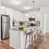 Kitchen with island, barstools, stainless steel appliances, white cabinetry