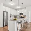 Kitchen with island, barstools, stainless steel appliances, white cabinetry