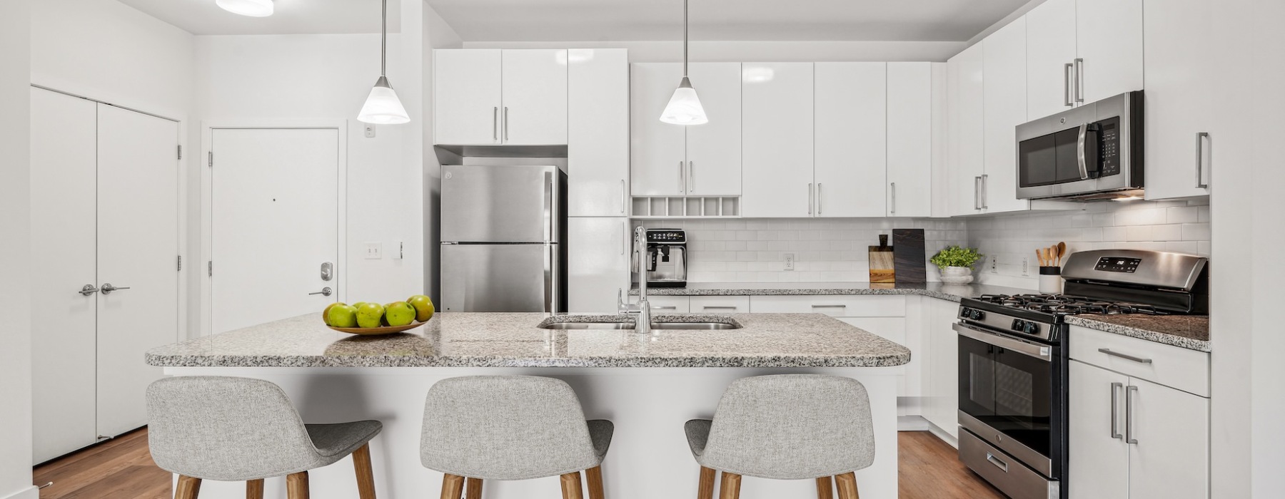 Kitchen with white cabinetry, stainless steel appliances and a kitchen island  with barstool seating