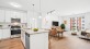 View of kitchen island, white cabinetry, and peek of living room and seperate dining area.