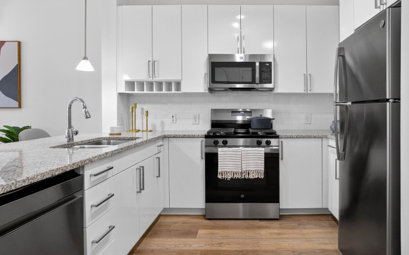 Model kitchen featuring wood grain floor paneling and stainless steel appliances at our apartments for rent in Stamford, CT.